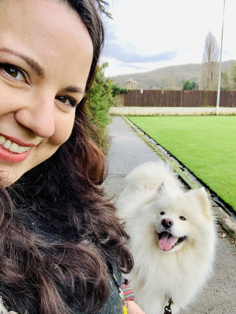 Emma Griffiths Voiceover smiling whilst with fluffy white dog on walk
